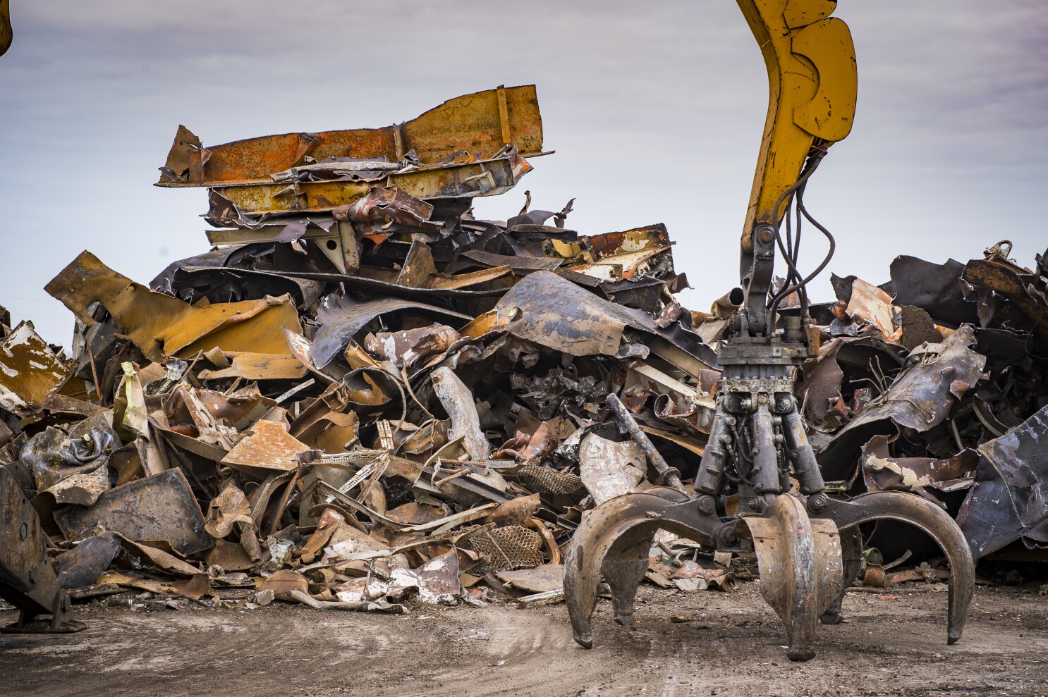 Large tracked excavator working a steel pile at a metal recycle yard, France Large tracked excavator working a steel pile at a metal recycle yard, France